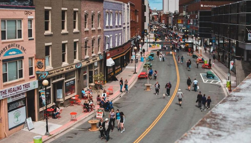 A downtown street of shops and sidewalk cafes, busy with people